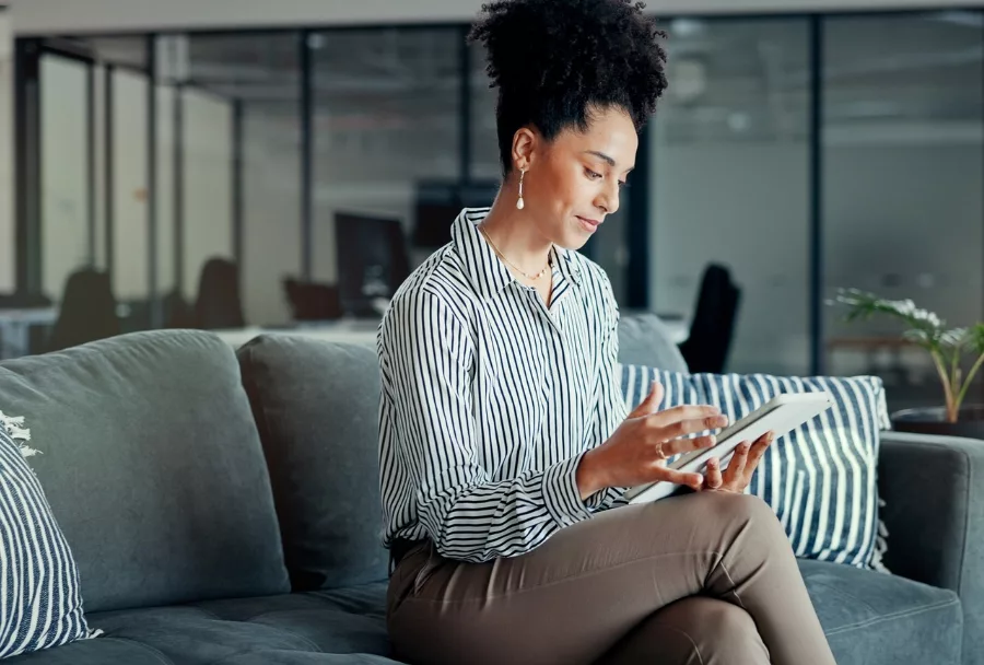 A busy woman in an office types a list into her tablet, illustrating Wise &Partners' experience serving female professionals, leaders and entrepreneurs